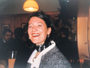 A young women with a big smile holding a glass in her hand