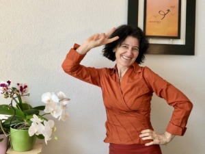 young smiling women wearing an orange blouse and skirt. in the background a picture with energy-on!