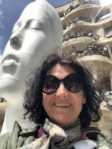 Wkoman with dark hair standing infront of a Gaudi house in Barcelona